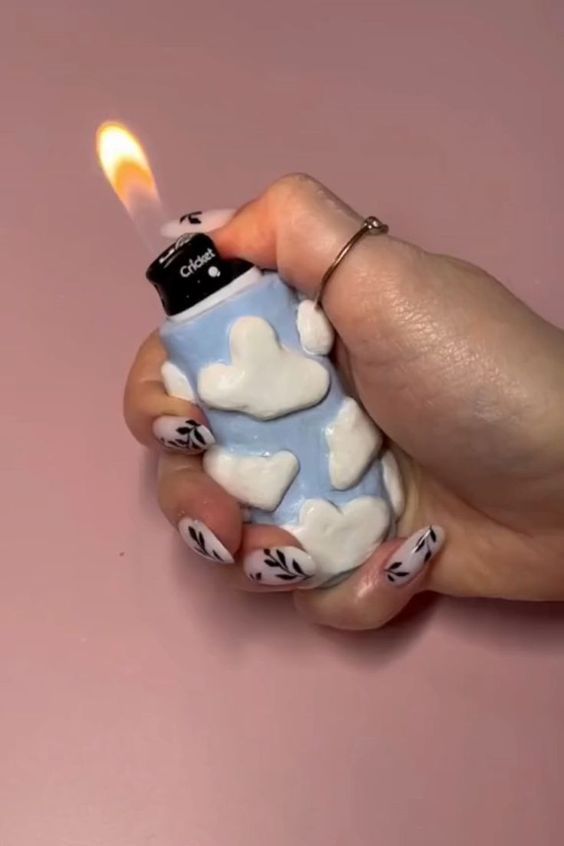 a person holding a lighter in their hand with clouds and hearts painted on the top