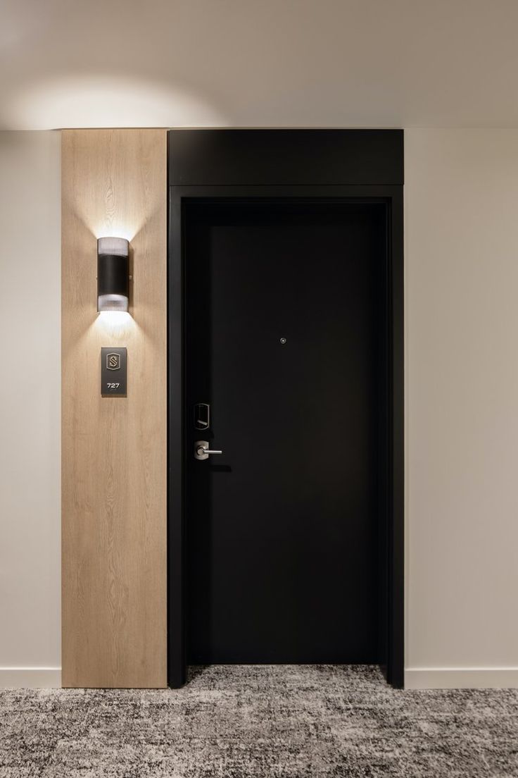 an empty room with a black door and some lights on the wall next to it