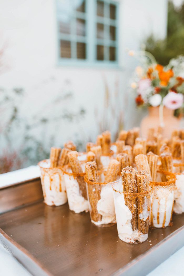 small desserts are arranged on a metal tray in front of a flower pot and window