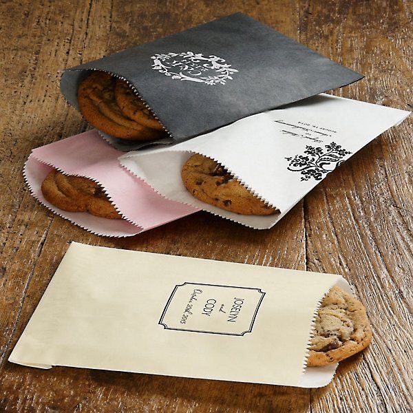 three bags with cookies in them sitting on a wooden table next to an envelope and paper bag