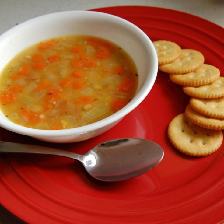 a bowl of soup and crackers on a red plate