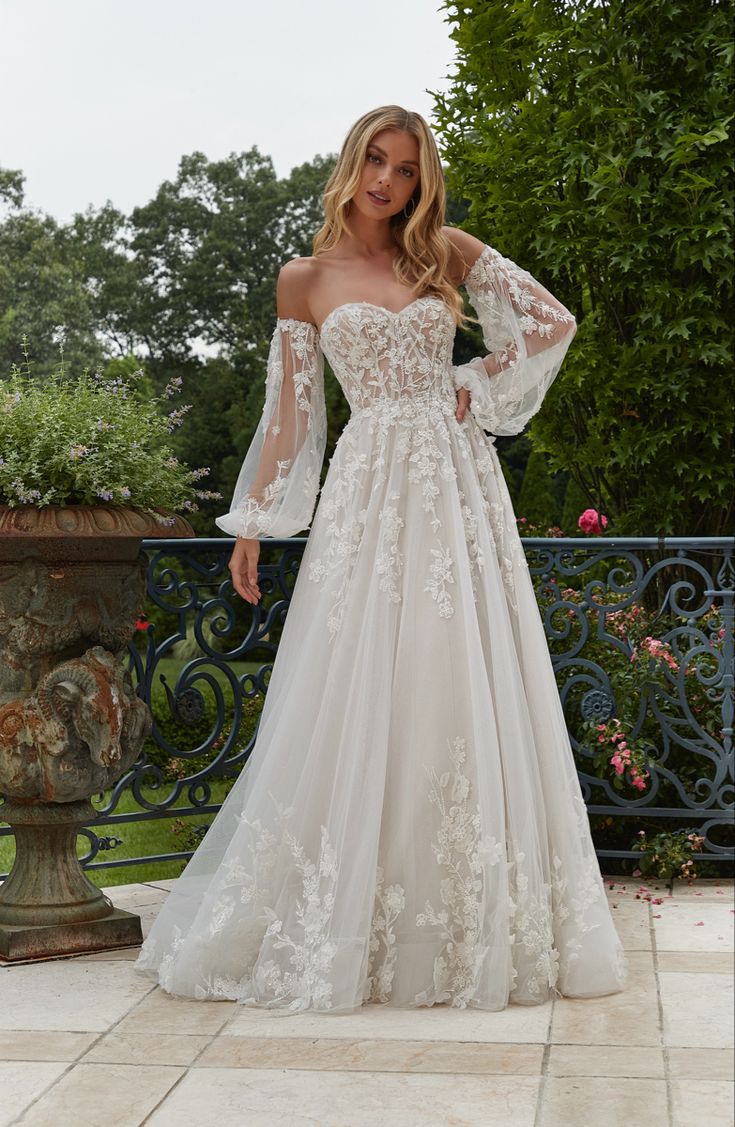 a woman in a white wedding dress standing on a patio with her hands on her hips