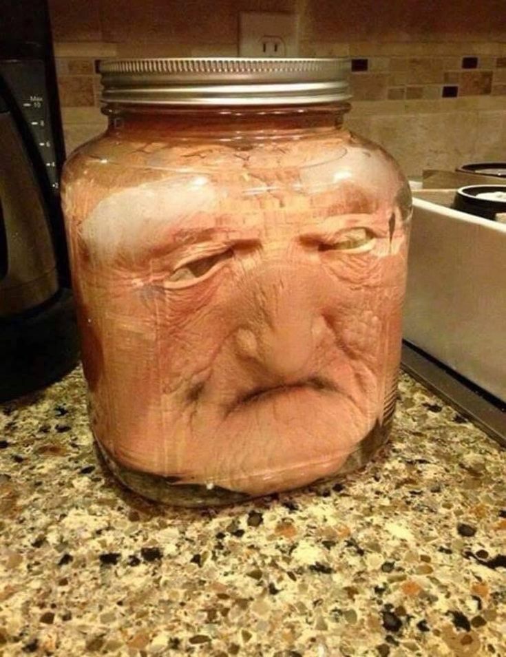 a jar with a face on it sitting on a counter top next to a toaster oven