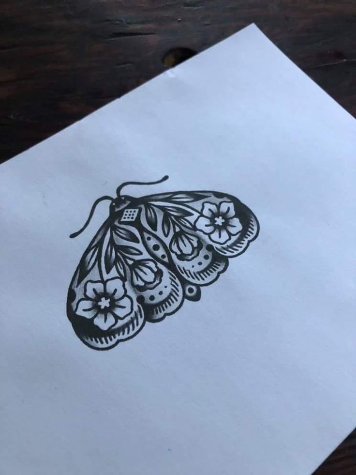 a piece of paper with a drawing of a butterfly on it sitting on a table