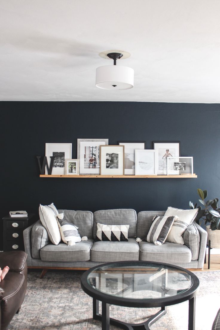 a living room filled with furniture and framed pictures on the wall above it's coffee table