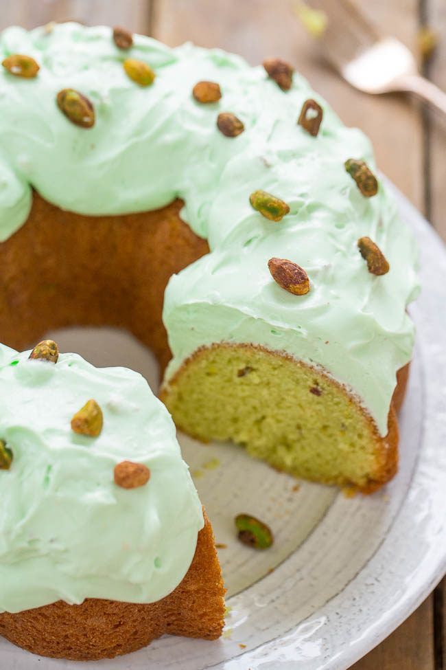 a bundt cake with frosting and pistachio toppings on a plate