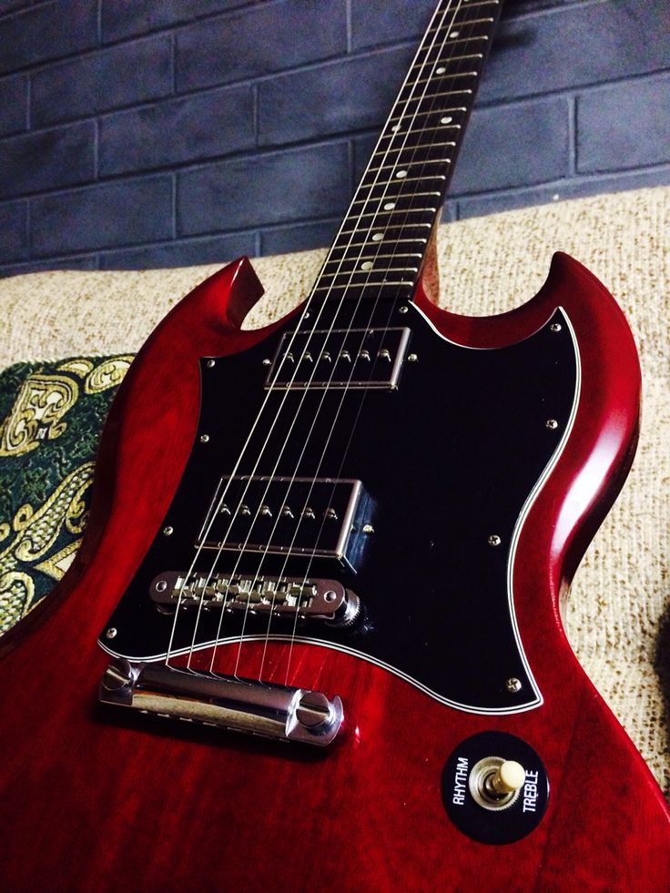 a red electric guitar sitting on top of a carpet