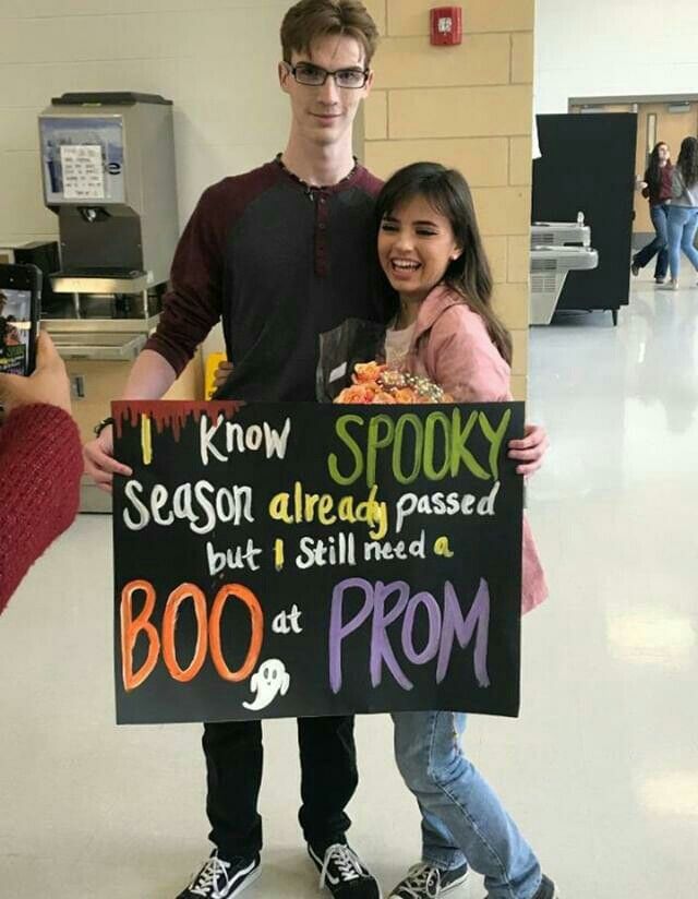 two people holding up a sign that says i know spooky but i still need a boo at prom