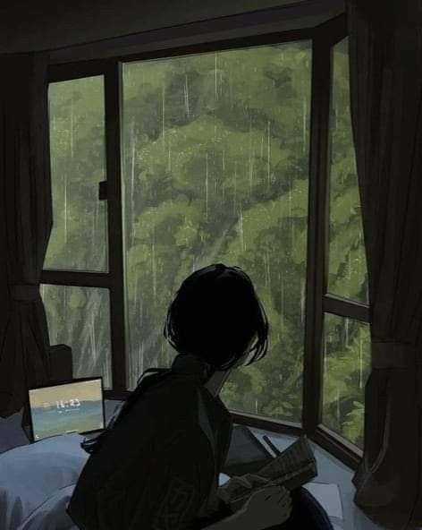 a person sitting on a bed in front of a window looking out at the forest