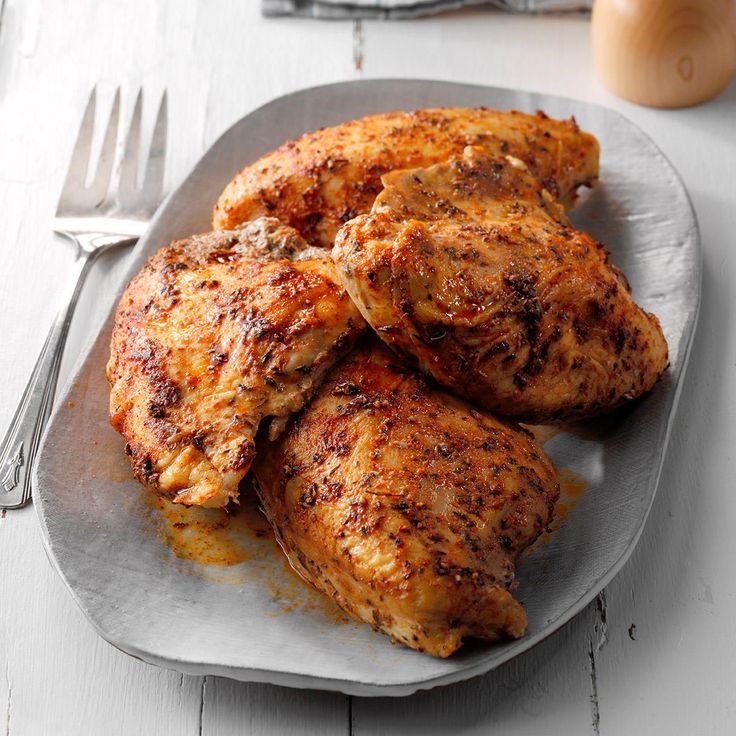 some fried chicken on a white plate with silverware