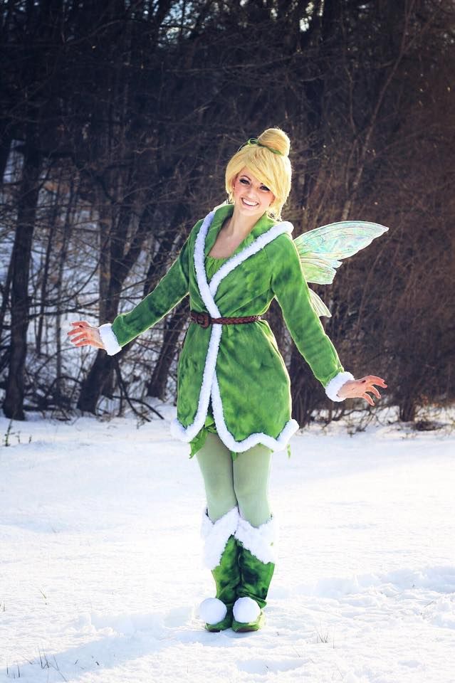 a woman dressed as tinkerbell standing in the snow with her arms outstretched and legs spread out