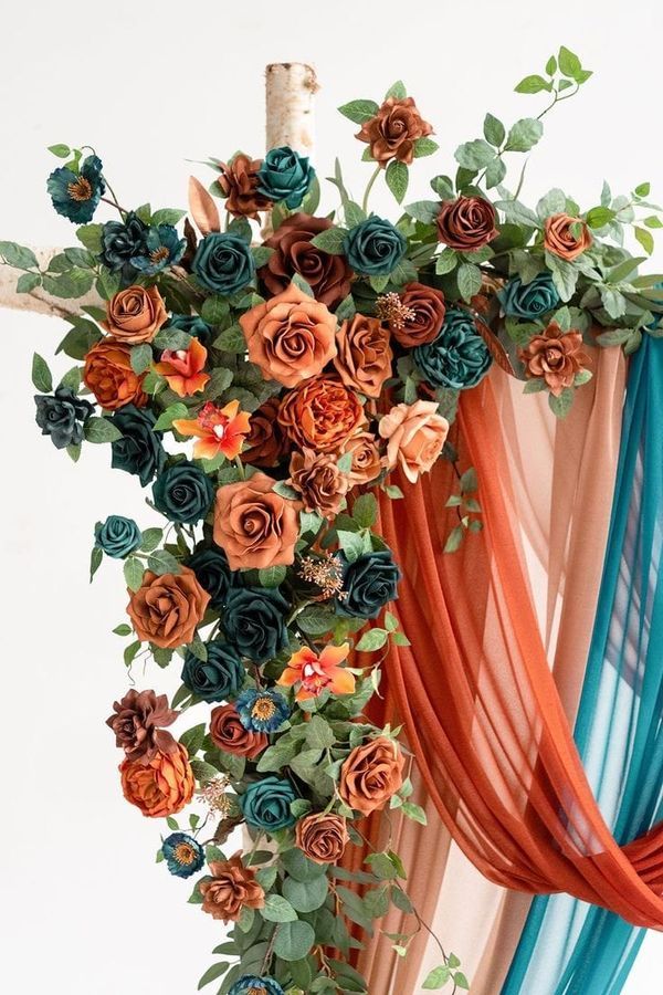 an arrangement of flowers is hanging from the ceiling in front of a drapeed curtain