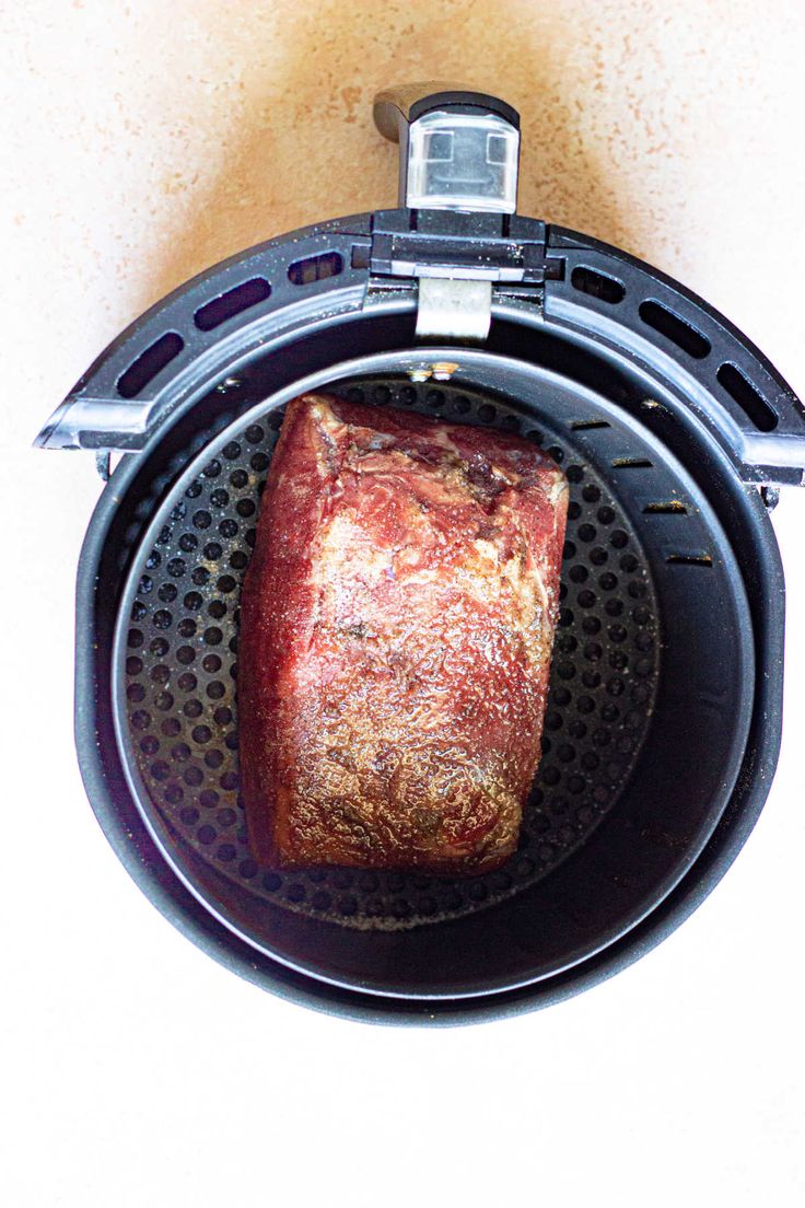 a piece of meat is sitting in an air fryer with the lid open and it's inside