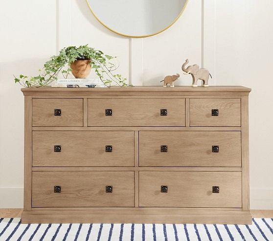 a wooden dresser sitting next to a wall with a mirror on it's side