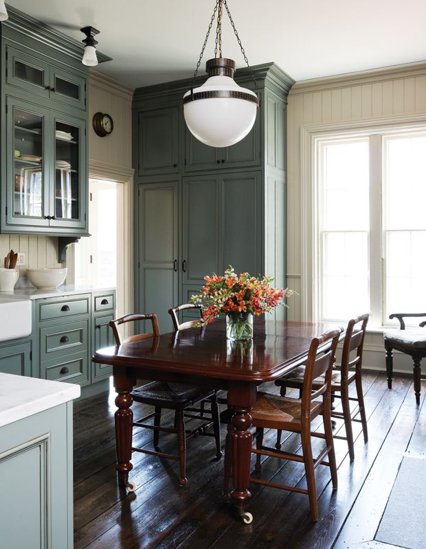 a dining room table and chairs in front of an open kitchen with lots of cupboards