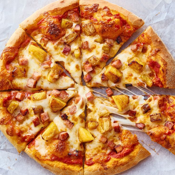 a pizza with pineapples, ham and other toppings cut into eight slices