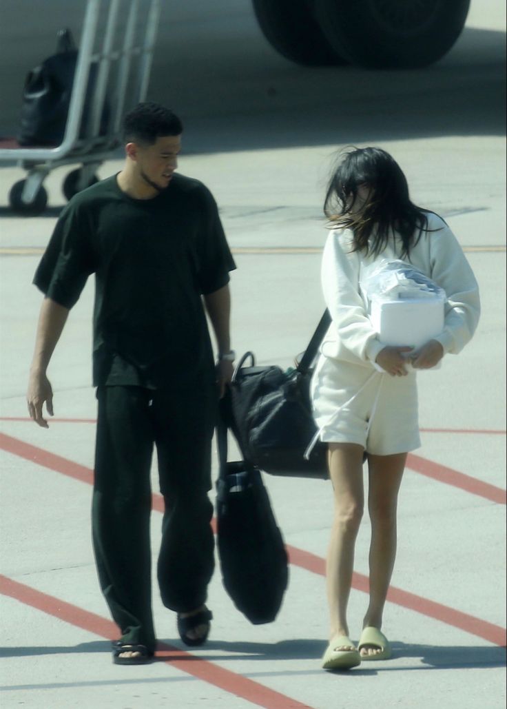 a man and woman walking down an airport tarmac