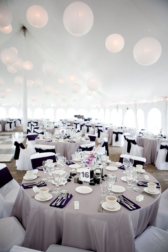 tables and chairs are set up in a tent for a formal function with white linens and black sashes