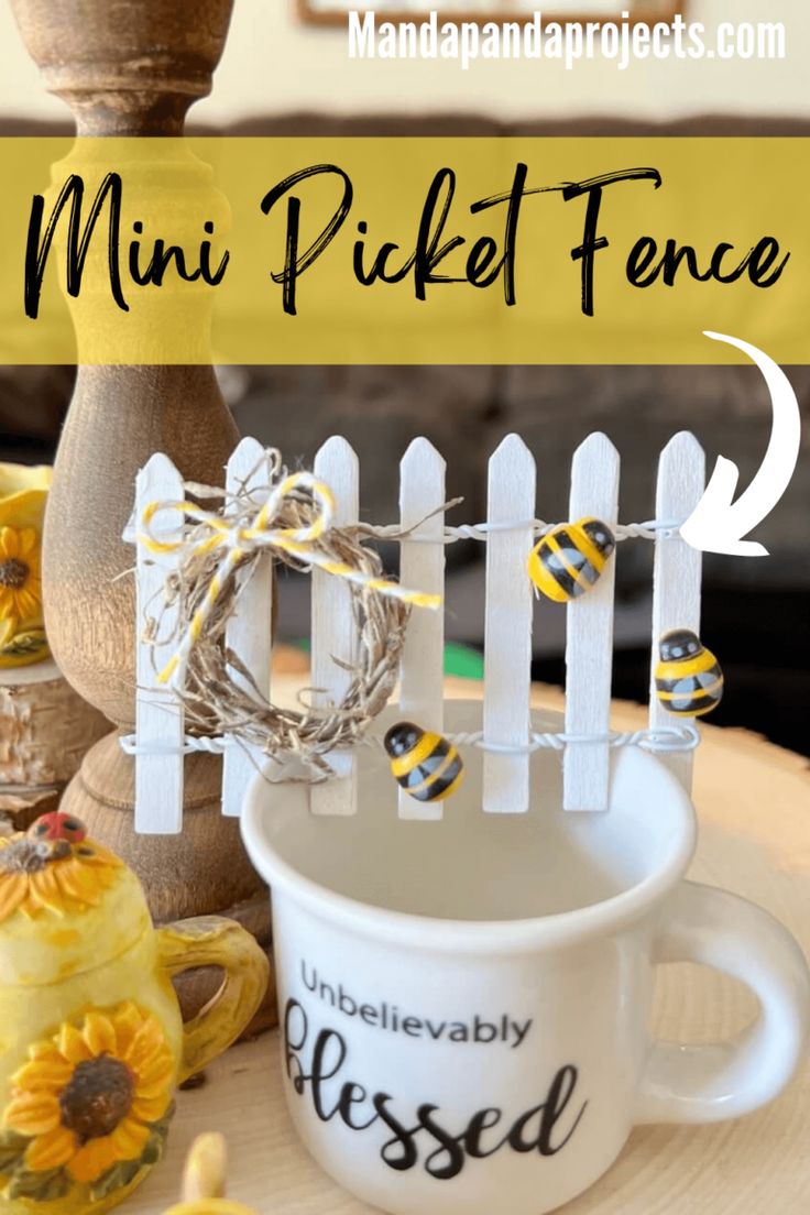 a coffee cup sitting on top of a wooden table next to a fence and sunflowers