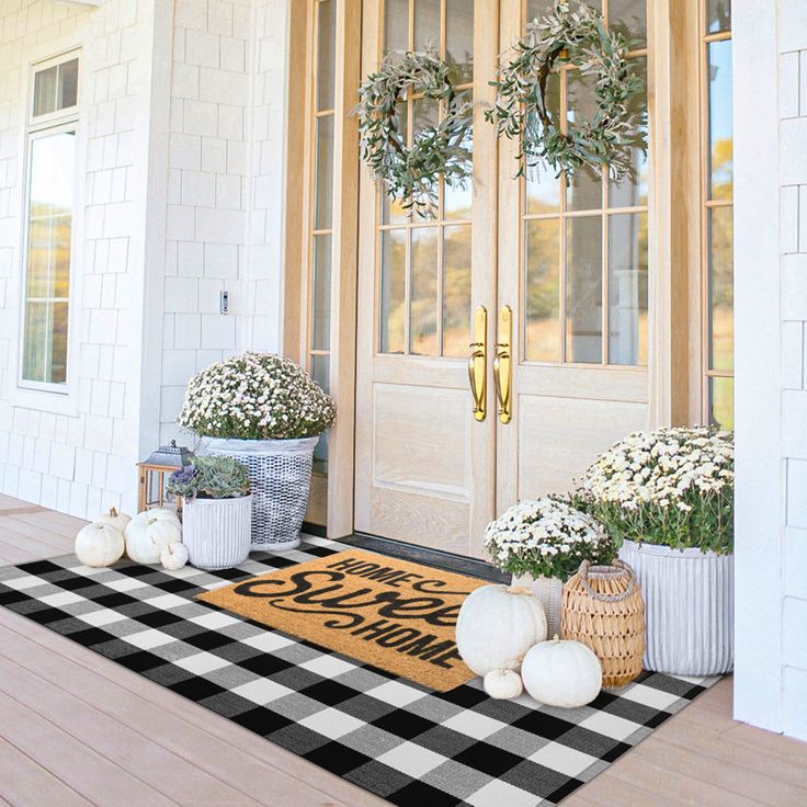 the front door is decorated with wreaths and potted plants