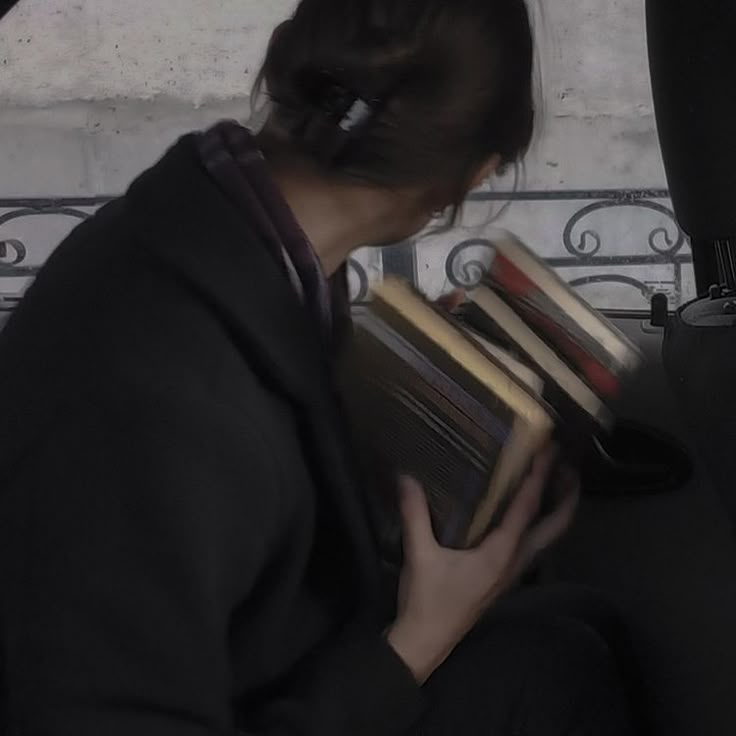 a woman sitting in the back seat of a car holding books