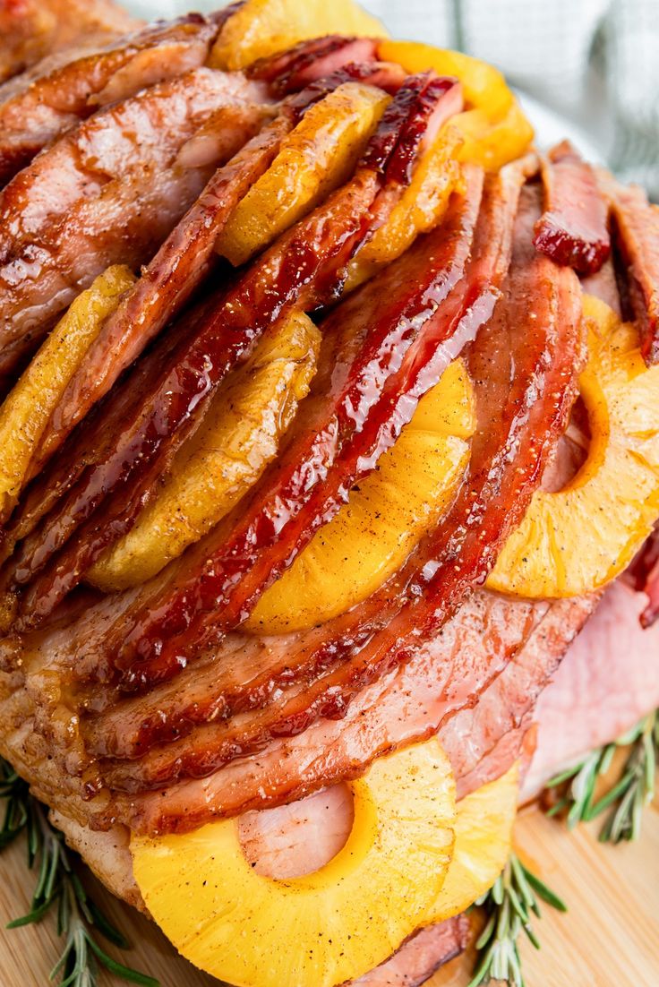 a ham and pineapple sandwich on a wooden cutting board with rosemary sprigs