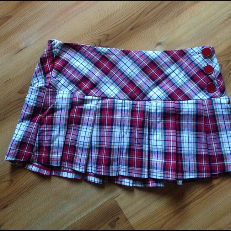 a red and white plaid skirt laying on top of a wooden floor