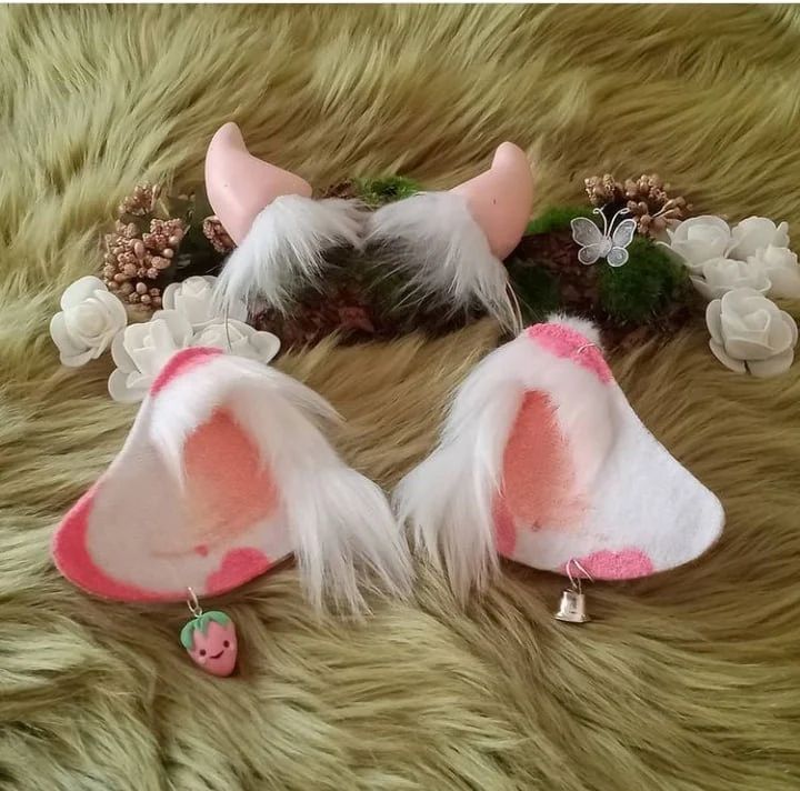 two pink and white furry animal ears laying on top of a fur covered floor next to flowers