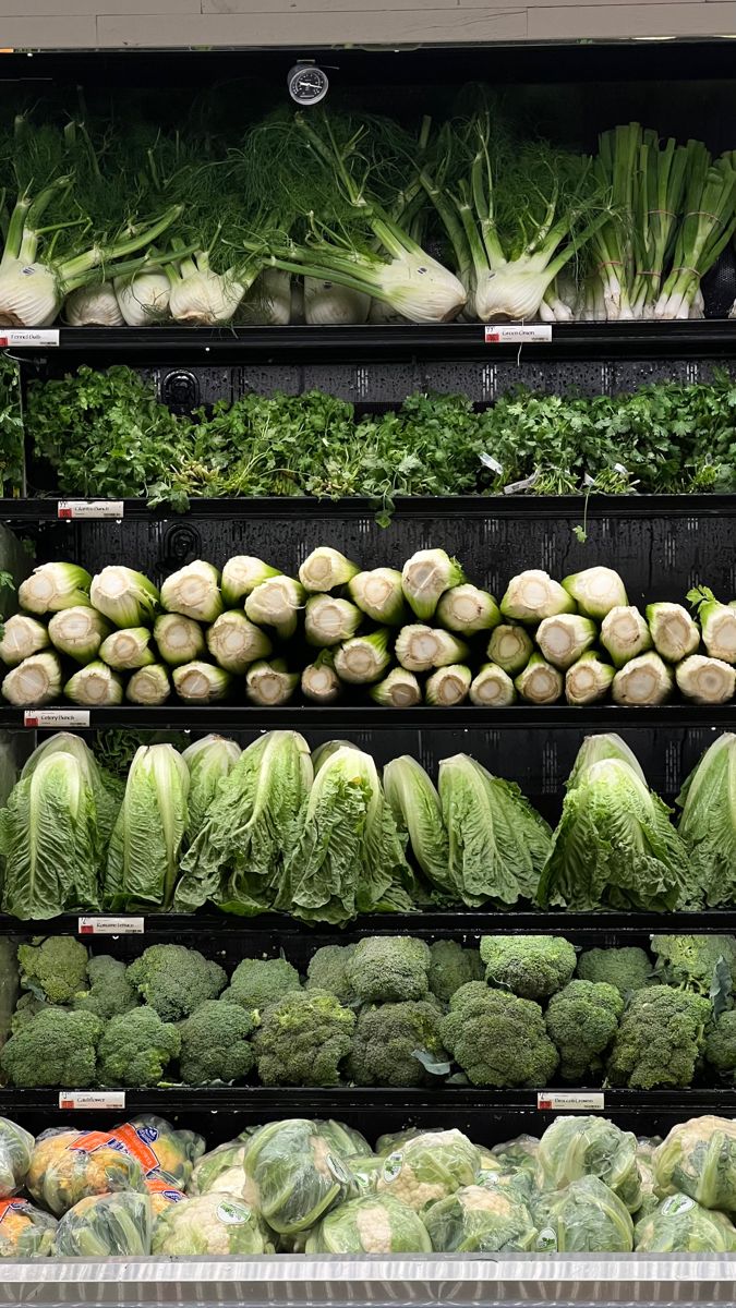 an assortment of vegetables on display in a grocery store, including lettuce and cabbage