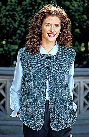 a woman standing in front of trees wearing a sweater vest