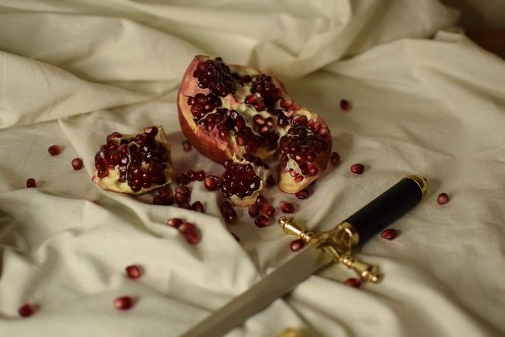 pomegranates are cut into pieces on a white sheet with a knife