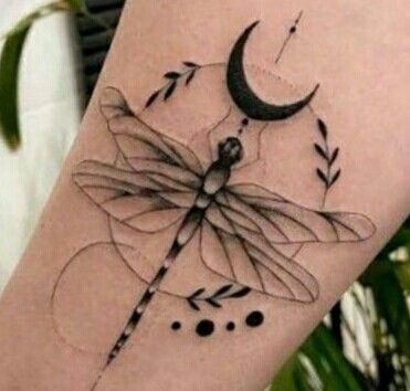 a dragonfly tattoo on the arm with an arrow in it's wings and a crescent