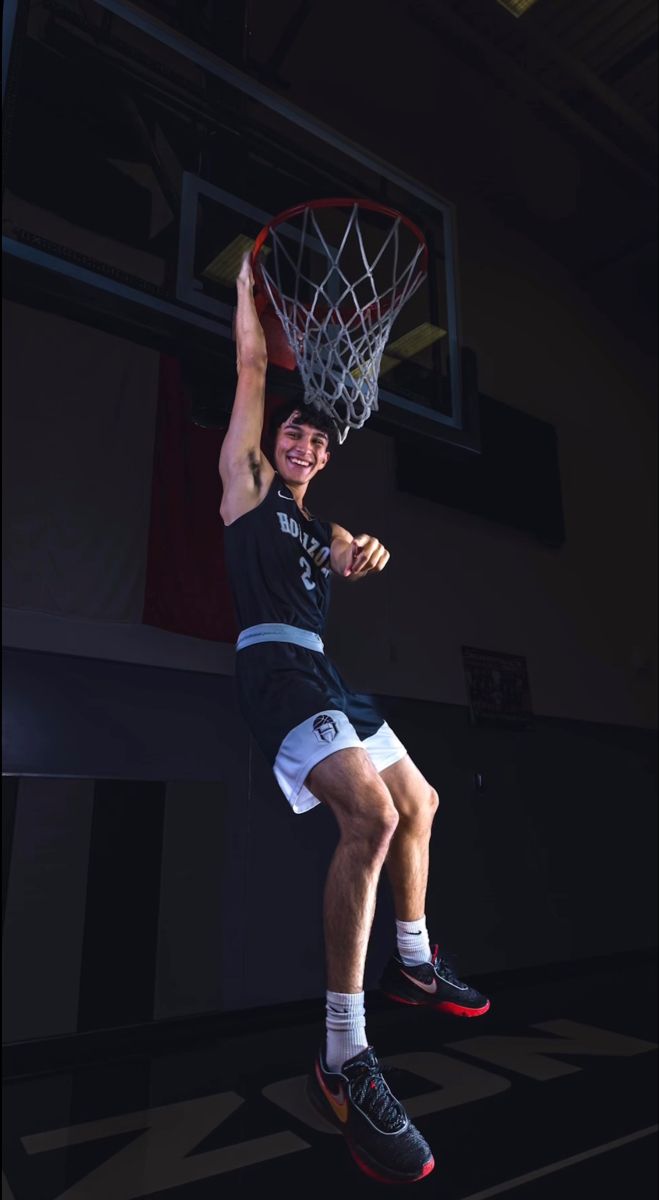 a basketball player is jumping up to dunk the ball in front of him with his hands