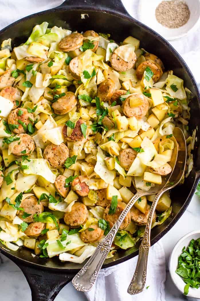 a skillet filled with pasta, meatballs and parsley on top of a white table