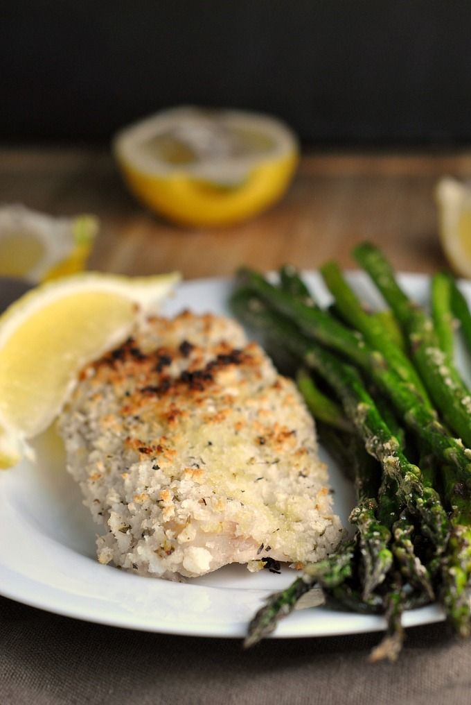 a plate with chicken, asparagus and lemon wedges on it next to some lemon slices