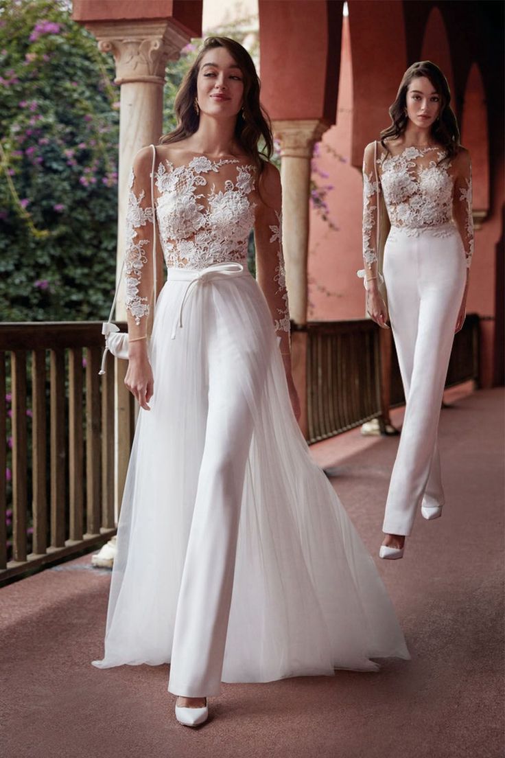 two women in white wedding gowns walking down the street