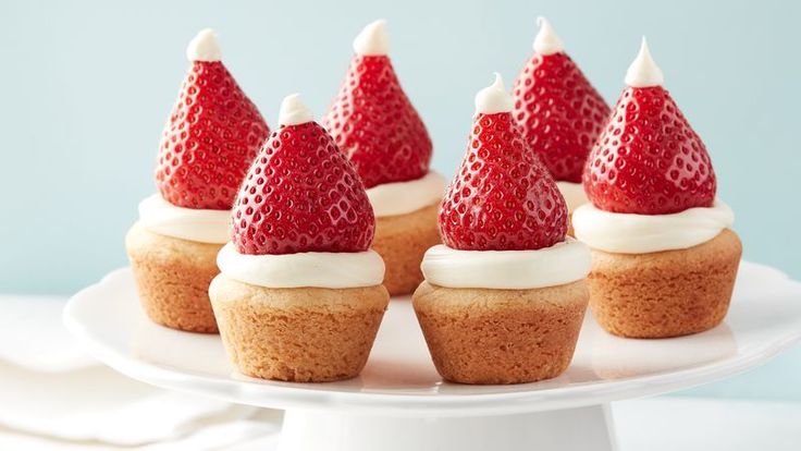 small cupcakes topped with strawberries on a white cake plate