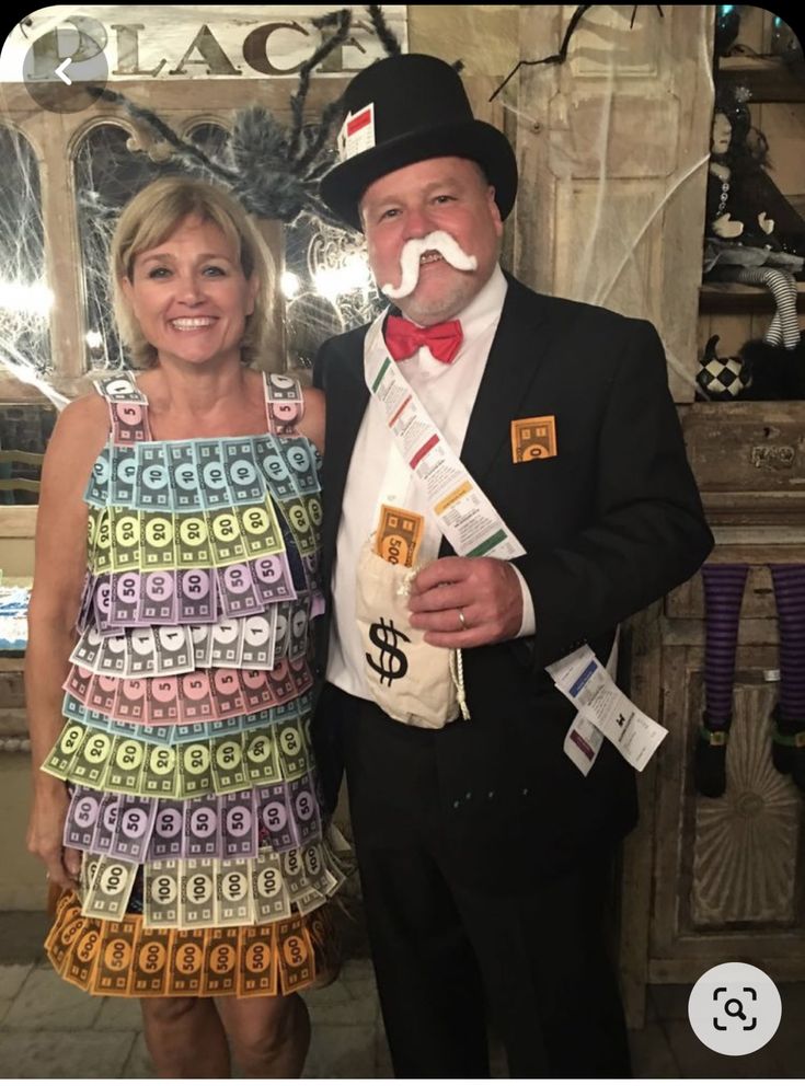 a man and woman pose for a photo in front of a mirror with fake moustaches on their faces