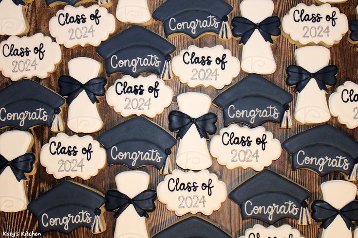 cookies decorated with graduation caps and gowns are displayed on a wooden table for the class of 2012