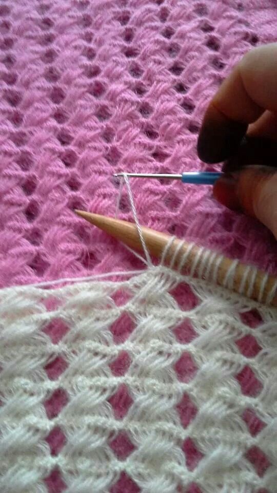 someone is crocheting on a pink blanket