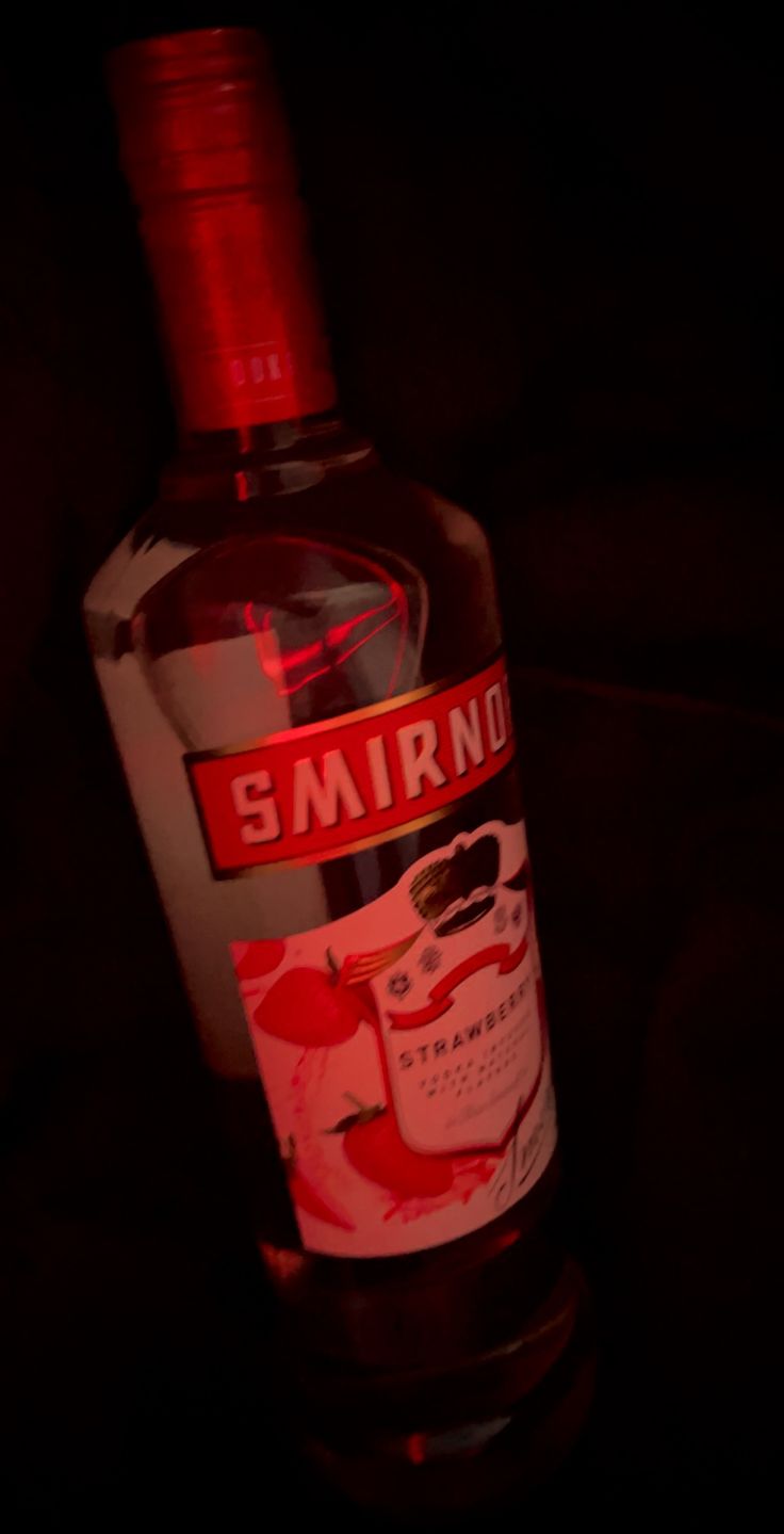 a bottle of smirno vodka sitting on a table with the light shining on it