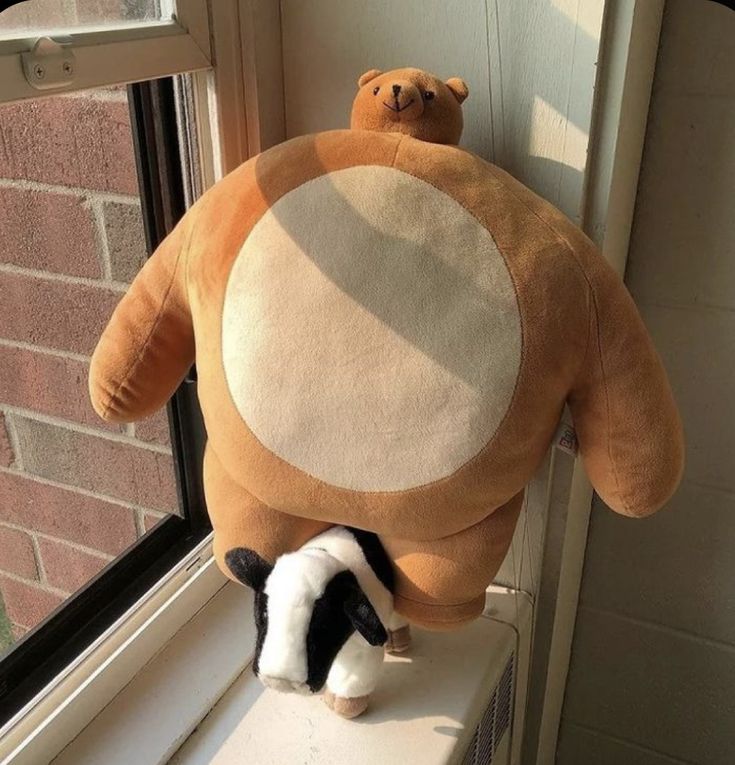 two stuffed animals sitting on top of a window sill