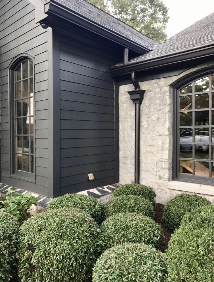 a black house with some bushes in front of it