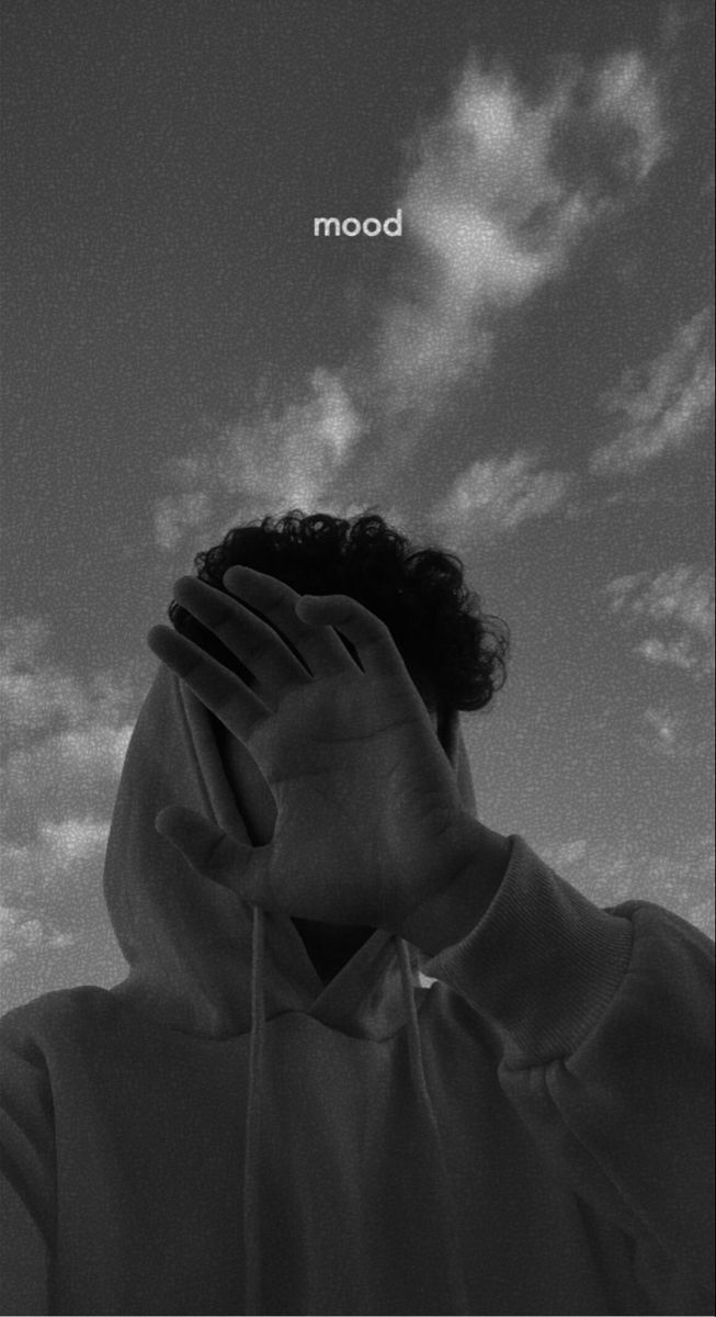 a black and white photo of a man covering his face with his hands under the hood