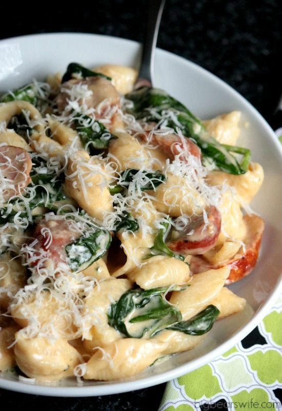 a white bowl filled with pasta and spinach