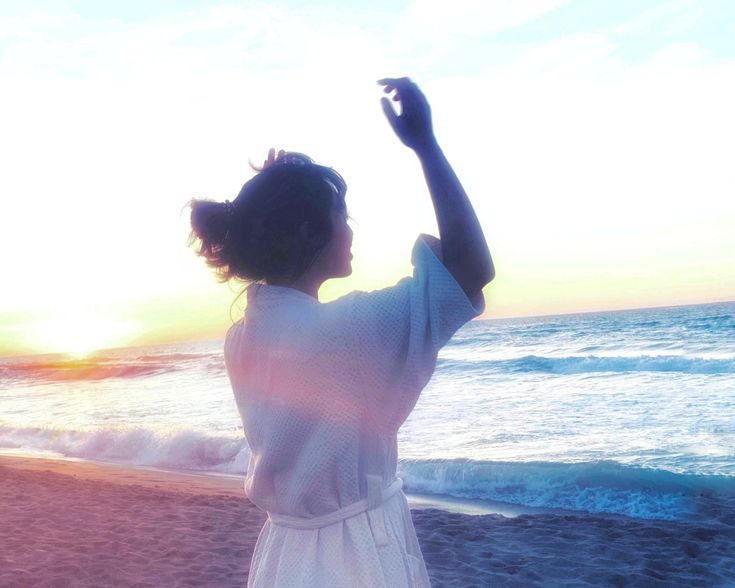 a woman standing on top of a beach next to the ocean