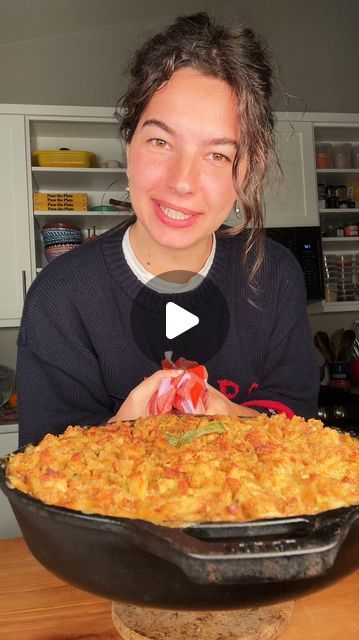 a woman sitting in front of a large casserole dish