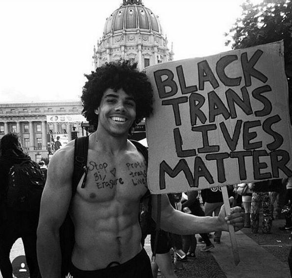 a man holding a sign that says black trans lives matter