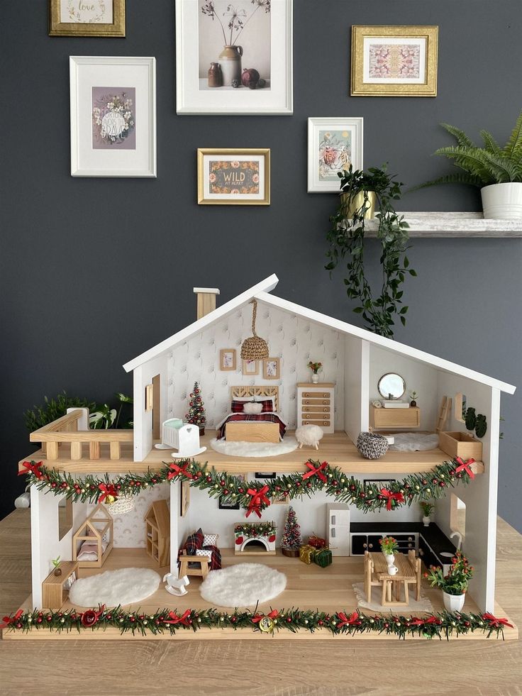 a doll house with christmas decorations and pictures on the wall in front of it,