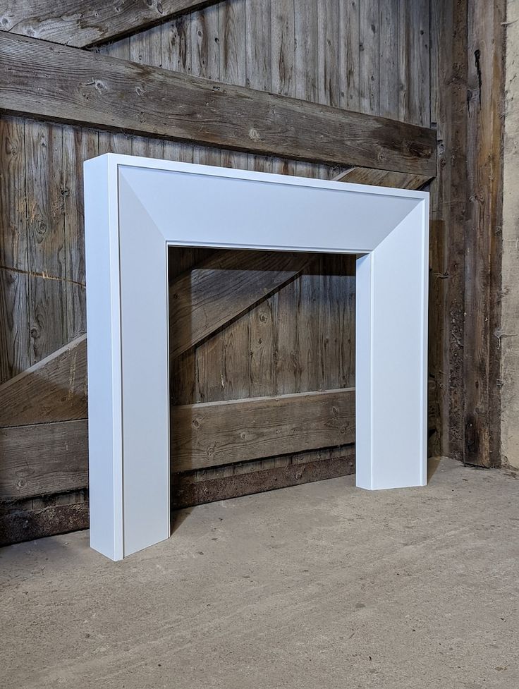 an empty white frame sitting in front of a wooden wall next to a stair case